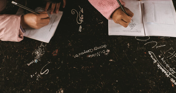 two girls at school drawing in their notebooks