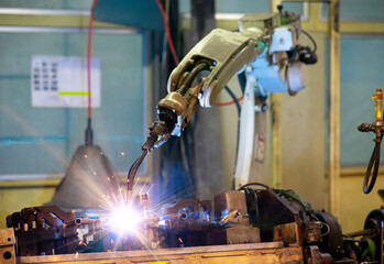 Sparkle flame on welding jig by industrial robot in production line of automotive plant