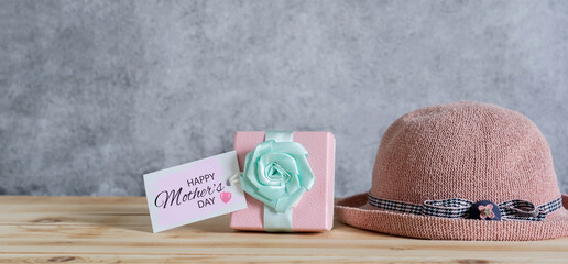 Objects on table of decoration Happy mothers day holiday background concept.Gift box with greeting card and pink hat.Blurred cement grey backdrop. copy space for design add text content. love mom.