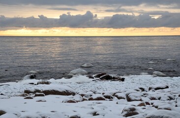 Snow winter shore with stones. The Gulf of Finland on sunset. scenery