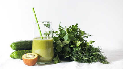 Green smoothie in a glass with kiwi, cucumbers, parsley and dill. The concept of healthy eating. Copy space.
