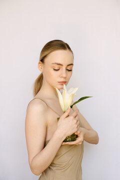 Sensual portrait of a young blond girl with a litle vase and a lily in it