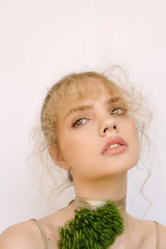 Sensual portrait of a young blond girl with a fluffy flower on the neck