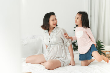 Happy family mother and child daughter play and laughing in bed