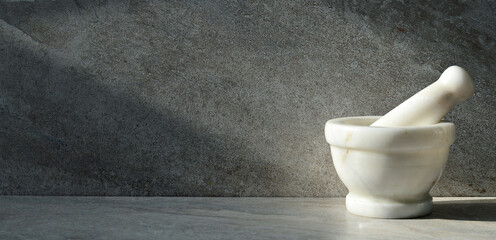 Mortar and pestle made of white stone on a gray marble background. Stylish interior mockup, copy...