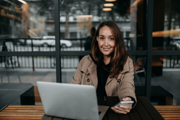 business focused confident successful freelancer adult woman blogger works using technology laptop phone communicates performs tasks studies in the workplace office in a public place in a coffee shop