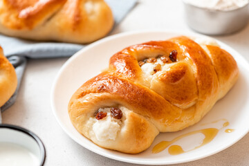 Homemade baking. Tasty sweet breakfast. Bun with curd filling in a plate on a white concrete background close-up