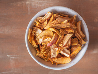 Sun-dried apples for a healthy snack in a deep light plate close-up