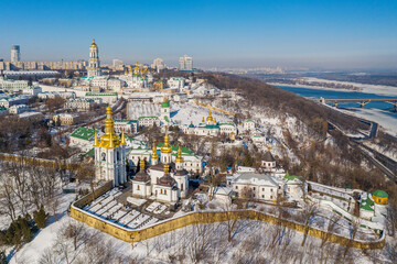 Beautiful winter top view of the Kiev-Pechersk Lavra. Many churches in the snow. Beautiful panorama of Kiev in the afternoon.