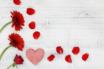 Red flowers with red heart on the white wooden background