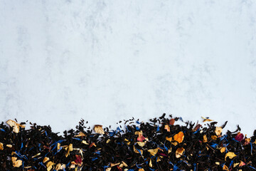 Black tea mixed with flower petals on a marble background