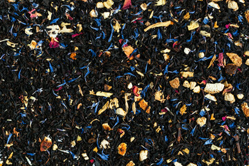 Black tea mixed with flower petals on a marble background