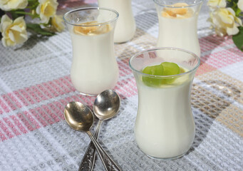 Italian dessert panna cotta in small transparent glasses decorated with grapes and banana on a checkered tablecloth