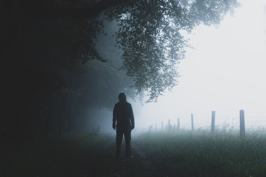 A man silhouetted on a countryside path. On a foggy, spooky day