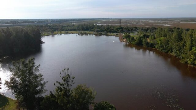 Aerial drone view towards a radio-controlled boat on a pond in Markham park, Florida