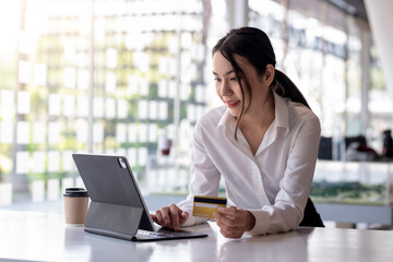 Young Asian businesswoman enjoy shopping online using credit card at a coffee shop.