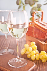 Glasses of white grape wine with grapes, wooden box and basket on the background