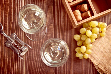 Glasses of white grape wine with grapes and wooden box on the background