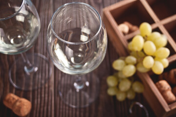 Glasses of white grape wine with grapes and wooden box on the background