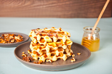 Freshly homemade baked waffles on the plate with honey on the wooden table