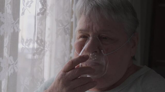 Senior Woman put on and breathing with an oxygen mask