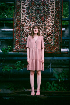 Girl wear a pink dress in front of a Russian traditional carpet