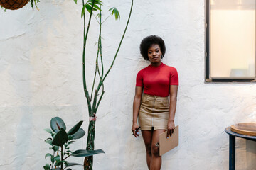 Portrait of attractive restaurant manager leaning on white wall looking at camera