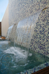 Vista lateral de dos fuentes de aguas cristalinas en una pared de azulejos azules y blancos de fondo.