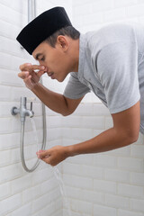 portrait of young Muslim man perform ablution (wudhu) before prayer at home