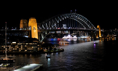 Night view of Sydney harbor bridge and North Sydney, boats sailing in the bay and Parramatta River. Focus on Bridge.