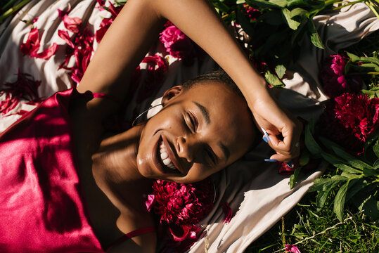 Portrait of a black girl smiles in a silk dress with a peony flowers