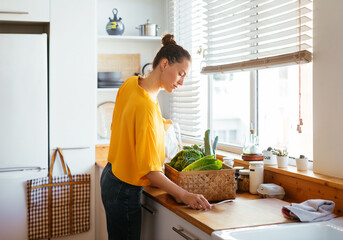 Woman with box of fresh vegetables reading paper card