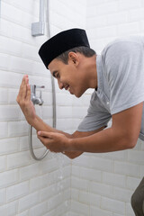 portrait of young Muslim man perform ablution (wudhu) before prayer at home. clean his hand