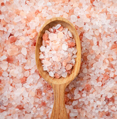 Fototapeta na wymiar Himalayan pink salt in a spoon on a salt background. Top view