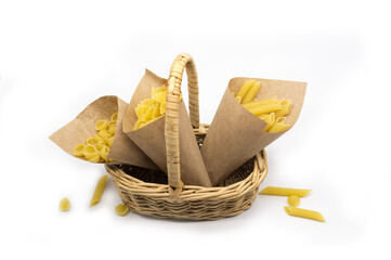 Obraz premium variety of pasta in paper bags in wicker basket isolated on white background. No plastic content. Replacing plastic bag. Eco package concept