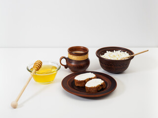 Rustic breakfast with healthy products in handmade antique crockery. Pottery. A cup of aromatic coffee, farm fresh cottage cheese, toasts with cottage cheese cream cheese and natural and fresh honey