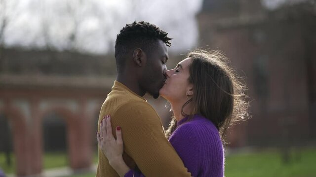 Interracial couple kissing and hugging each other outside. Black man and white girl embrace and love