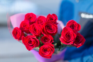 Man holds flowers.Bouquet in the man hand. Flower congratulations for women.Male hand with red roses closeup.Hand with flowers.Man with flowers. Hand holdihg givind roses. 8 March, Mother's Day