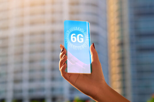 Close up of a woman hand holding a futuristic transparent Phone with 6G connection . Future technology . 6th generation high speed mobile internet concept . 