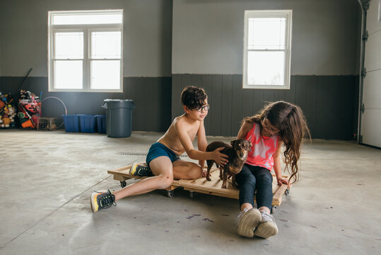 Young Boy And Girl Sitting On Scooters.