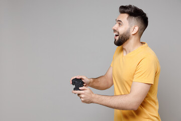 Side profile view on young caucasian smiling bearded happy excited student gamer man 20s winner...