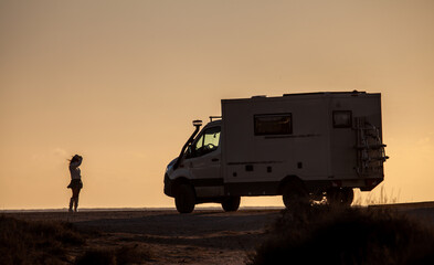 woman silhouette is posing  for photographer in front of offroad motorhome truck in the evening...