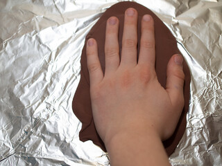 imprinting a child's hand of a boy on polymer clay.