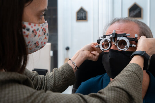 Ophthalmologist Doing Vision Tests To An Older Man With White Hair Trying To Read. Hyperopia Test. Eyestrain Test.