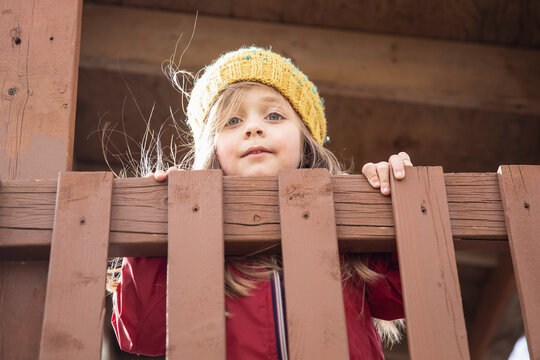 Pretty blond girl with yellow knit hat playing outside on a chilly spring day