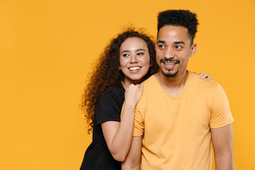Fototapeta premium Young romantic couple friends together family african pensive wistful dreamful woman man 20s in black yellow tshirt boyfriend hug girlfiend looking aside isolated on orange background studio portrait