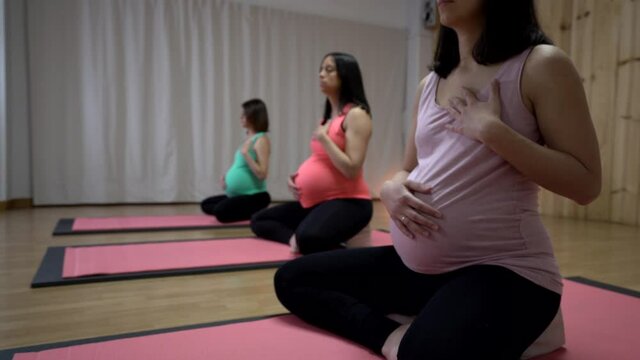 Group of pregnant women practicing yoga in a wooden yoga studio with a magical atmosphere.