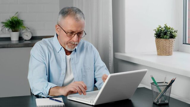 Older man feels rage as he looks at the laptop screen.