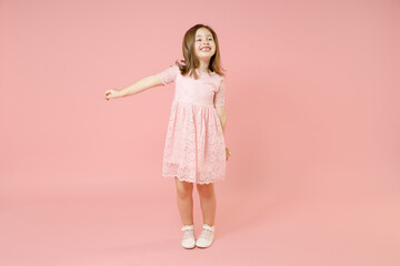 Full length of little kid girl 5-6 years old wears rosy dress have fun dancing fooling around celebrate play isolated on pastel pink background child studio portrait. Mother's Day love family concept.