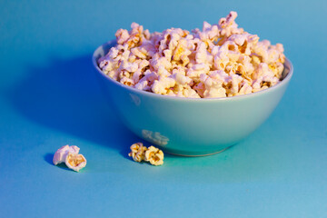 Bright pictures of popcorn. Popcorn in a blue plate. Blue background. Flat lay, copy space. Banner